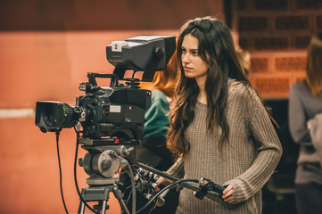 Behind the scene. Female cameraman shooting film scene with camera