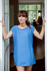 Woman in blue dress standing in french window