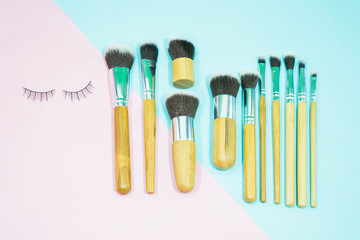 Set of makeup brushes on pink and aqua colored composed background. Top view point, flat lay