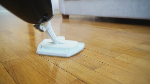 Cleaning the floor with a dry steam cleaner.