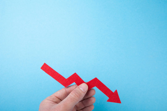 Falling red arrow down from the chart in hand on a blue background. Copy space.