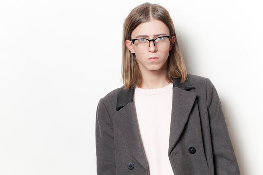 Androgyne young man with coat on white background. Studio portrait