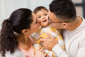 happy mother and father kissing baby daughter