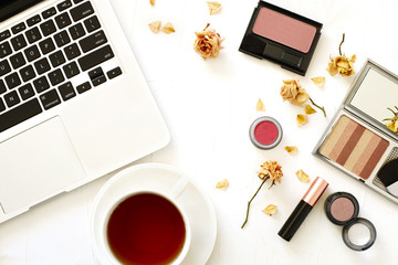 Flat lay with laptop, cup of tea and woman make up products on white background