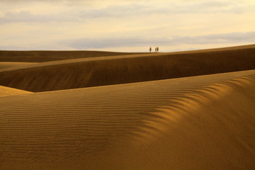 Fototapeta na wymiar People walking on sand dunes in Maspalomas, Gran Canaria.