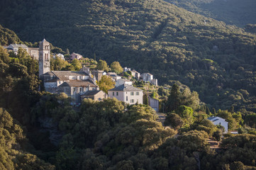 Fototapeta na wymiar Corsica, 28/08/2017: la macchia mediterranea con vista sullo skyline di uno dei remoti villaggi dell'Alta Corsica sul lato ovest del Capo Corso, famoso per i suoi paesaggi selvaggi