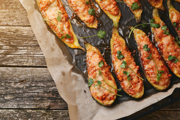 Baked stuffed zucchini with meat in a pan on wooden boards.