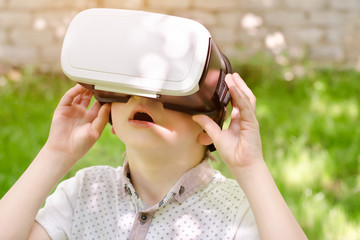 Boy in a virtual reality helmet on a background of green grass