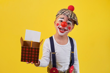 Funny kid clown isolated on yellow background. Beautiful playful portrait child boy jester in...