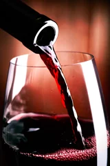 Papier Peint photo Vin Verser du vin rouge dans le verre sur fond de bois