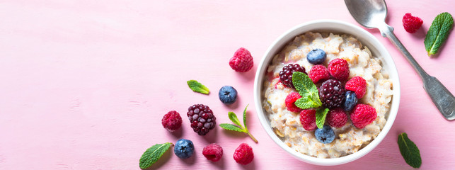 Oatmeal cereal with milk and berries top view.