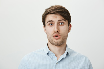 Guy is startled and stunned of seeing someone very ugly. Portrait of shocked and confused handsome man tilting head backwards, gasping from surprise while standing over gray background