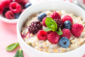 Oatmeal porrige with milk and berries close up.