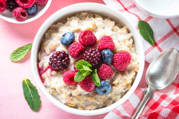 Oatmeal porrige with milk and berries top view.