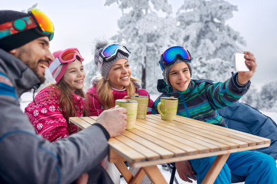 Family enjoying on tea and making selfie at ski resort