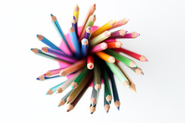 Bunch of multicolored pencils in the plastic glass on white background, view from top