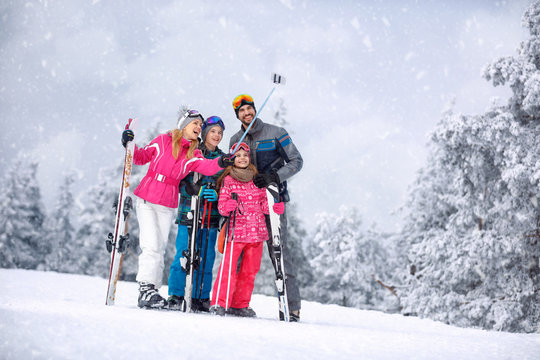 Skiing, winter, snow and fun - family enjoying winter vacations and making mobile selfie