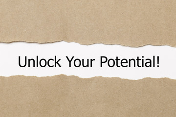 The text Unlock Your Potential appearing behind torn paper. 