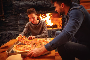 Smiling father and son eating pizza together