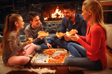 Smiling parents and children have fun and eating pizza