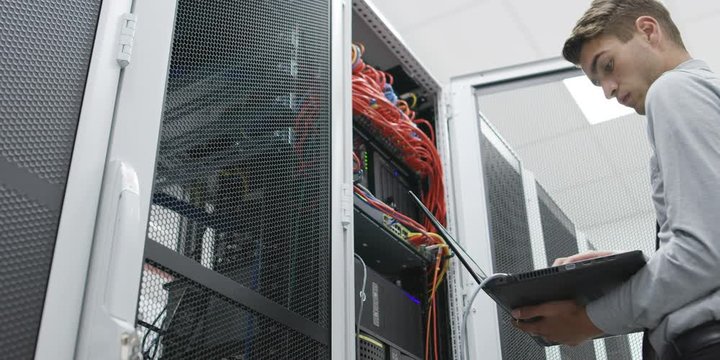 man working on his laptop in server room. Shot on RED Helium 8K