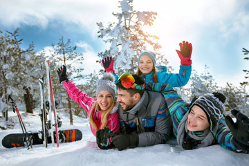 family enjoying winter vacations in mountains on snow - obrazy, fototapety, plakaty