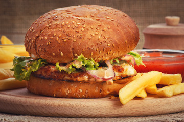 Chicken burger with fried potato on wooden plate