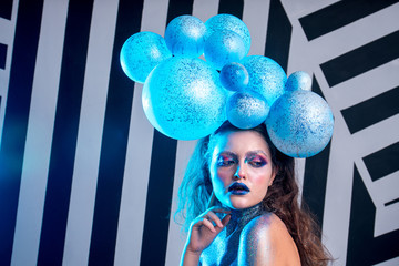 Young attractive girl in makeup, in glasses and balloons on the head
