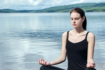 Fototapeta na wymiar girl doing yoga meditation by lake