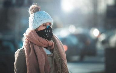 Young woman wearing protective mask in the city street, smog and air pollution - obrazy, fototapety, plakaty