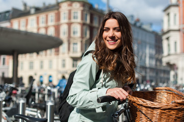 Fototapeta na wymiar Young happy woman on bicycle looking at camera and smiling in the city of Copenhagen, Denmark. Activity, healthy lifestyle and environmentally friendly transport