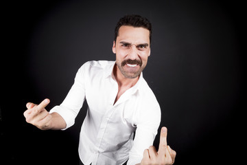 Young handsome man showing fuck off hand gesture