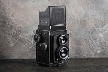 The old medium-format TLR camera on cement wall background.