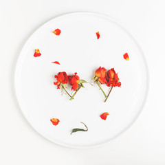 two images of a heart made of buds of dry flowers of roses on a white plate