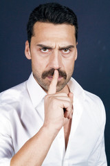 Young handsome man with beard and mustache showing hush sign