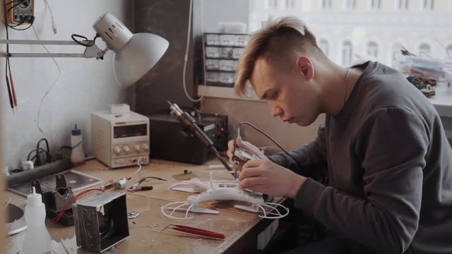 Prfessional is working on a drone with a soldering iron