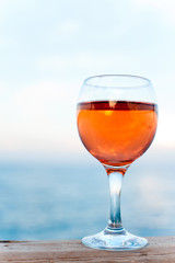 Glass of fresh soft rose wine on wooden pier