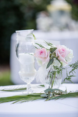 Table Decor with White and Pink Rose Floral Arrangement in Glass Vase with White Candle