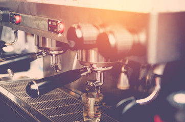 prepares espresso in his coffee shop ; close-up , vintage tone
