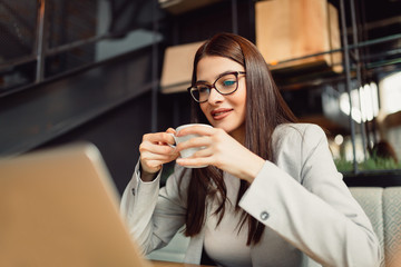 Beautiful businesswoman enjoying a coffee in front of her laptop computer