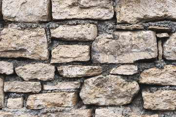 Close-up textured background is an irregular natural stone wall made of different stones without a cement-type bonding mixture. Medieval background