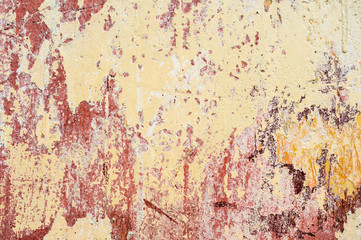 Textured background of multi-layer flaking paint on the wall. Mixing different colors of paints in the cleaved layers on the surface. Grunge texture with a deep pattern