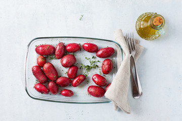 raw red potatoes in oil with spices on a resistant oven tray or Glass Oven Dish, ready to be baked in the oven