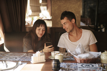 people, technology, lifestyle and dating concept - happy couple with smartphone drinking coffee and smoothie at cafe