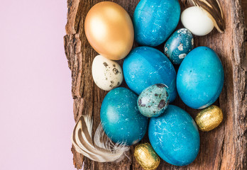 Fototapeta na wymiar Easter turquoise and gold eggs on light pink background, minimalism, modern decoration, text space.