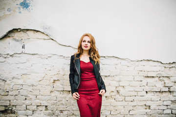 beautiful girl in a burgundy dress against a white wall background. In a burgundy dress with beautiful hair and makeup