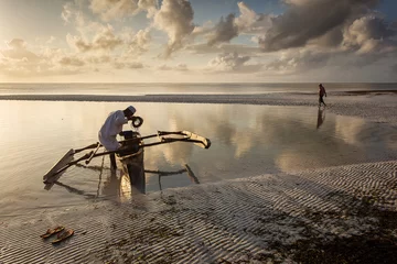 Foto op Canvas Fishermen going on ocean on traditional fishing boat in Zanzibar with storm clouds at sunrise © danmir12