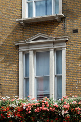 The white window on the brick wall is decorated with flowers