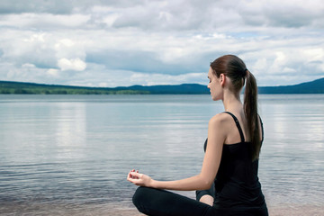 girl doing yoga meditation at peaceful lake in Norway 