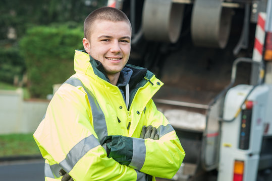 young municipal garbage collector near garbage truck